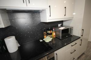 a kitchen with white cabinets and a black counter top at Osterley Place - Apt A in Hounslow