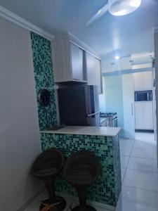 a kitchen with a counter and two stools in it at Apto novo com ampla sacada e piscinas in Guarujá