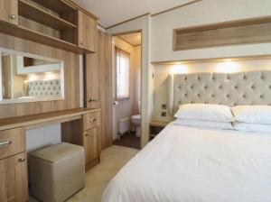 a bedroom with a bed and a sink and a mirror at 23 Gull Court in Porthmadog
