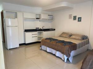 a bedroom with a bed and a white refrigerator at 101 - Saint Sebastian Flat in Jaraguá do Sul
