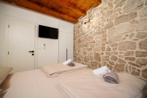 a bed in a room with a stone wall at Stone House Dida Toni Tribunj in Tribunj