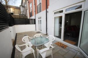 a patio with a glass table and white chairs at Osterley Place - Apt F in Hounslow