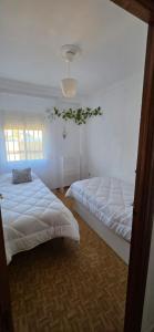two beds in a room with white walls at Sevilla Gateway a 10 min Sevilla y cerca aeropuerto, 3 habitaciones, 2 camas en cada habitación y sofá cama in Alcalá de Guadaira