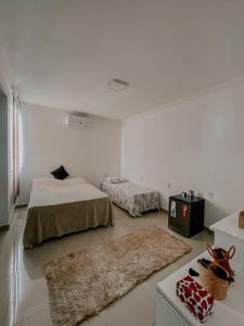 a white room with two beds and a rug at Suítes em casa ampla com área gourmet in Uberlândia