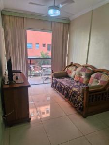 a living room with a couch and a table and a television at Apto novo com ampla sacada e piscinas in Guarujá