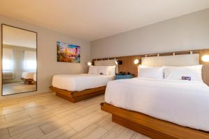 a hotel room with two beds and a large mirror at TRYP by Wyndham Mayaguez in Mayaguez