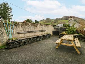 a wooden picnic table next to a stone wall at Yr Hen Ysgoldy in Machynlleth
