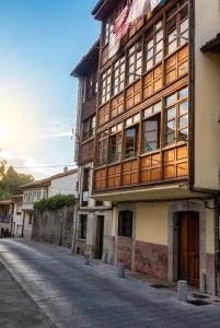 a tall building with wooden windows on a street at Apartamentos El Cuetu in Llanes