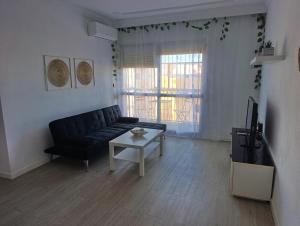 a living room with a black couch and a table at Sevilla Gateway a 10 min Sevilla y cerca aeropuerto, 3 habitaciones, 2 camas en cada habitación y sofá cama in Alcalá de Guadaira
