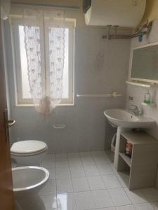 a bathroom with a toilet and a sink and a window at Home Room in San Pietro Avellana