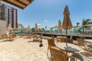 an outdoor patio with tables and chairs and umbrellas at Condominium w/ pool and steps fr/ the beach - SRCs in Ilhéus