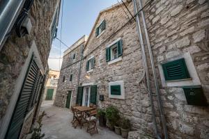 an alley with a table and chairs in a stone building at Stone House Dida Toni Tribunj in Tribunj