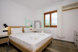 a guest bedroom with a bed and a window at Elaion House in Agia Paraskevi