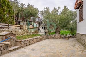 a stone courtyard with a stone wall and a house at Elaion House in Agia Paraskevi