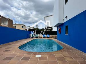 a swimming pool in the courtyard of a blue building at Sa Torreta 1 in Cala Blanca