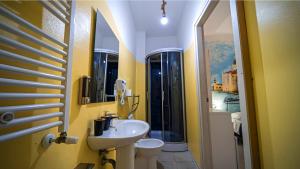a yellow bathroom with a sink and a toilet at Bed Rho Stazione - Fiera in Rho +27 photos