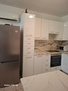 a kitchen with white cabinets and a stainless steel refrigerator at SUNNY COAST in Paralimni +11 photos
