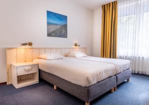 a bedroom with a large bed in a room at Hotel de Burg in Domburg