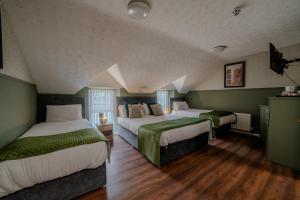 two beds in a room with green walls and wooden floors at Castle Inn in Newtownstewart