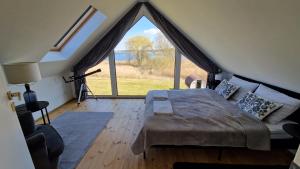 a bedroom with a bed and a large window at Maxim Domki nad Jeziorem in Załęże