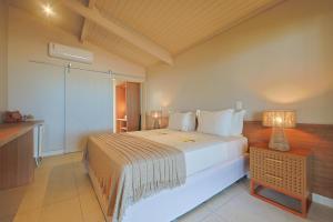 a bedroom with a large white bed and a table at Estalagem Caiuia in Japaratinga +57 photos