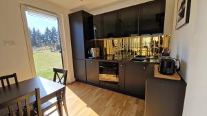 a kitchen with black cabinets and a table and a counter at Maxim Domki nad Jeziorem in Załęże