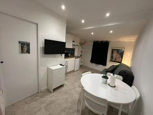 a living room with a white table and a room with a tv at Léopard vert - Clim - Tout inclus in Aubagne