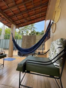a hammock and a chair on a porch at Casa Aconchego do Mar in Japaratinga
