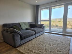 a gray couch in a living room with windows at Littlestone Seaside Retreat in Littlestone-on-Sea +22 photos