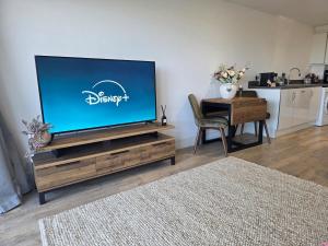 a living room with a flat screen tv on a wooden entertainment center at Littlestone Seaside Retreat in Littlestone-on-Sea