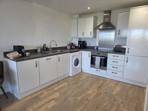 a kitchen with white cabinets and a washer and dryer at Littlestone Seaside Retreat in Littlestone-on-Sea