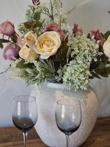 a vase with a bouquet of flowers and two wine glasses at Littlestone Seaside Retreat in Littlestone-on-Sea