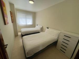 two beds in a small room with a window at A Riveira in Muxia