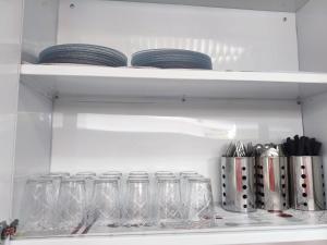 a shelf with glasses and plates in a refrigerator at Hostel Vila Universitária in Bauru
