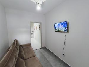 a living room with a couch and a television on the wall at Hostel Vila Universitária in Bauru