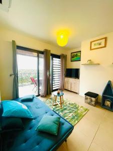 a living room with a blue couch and a large window at Heinoa Lodge Papeete in Papeete