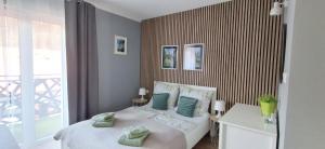 a bedroom with a white bed with green pillows at Idylla Apartamenty Gościnne blisko centrum in Kudowa-Zdrój