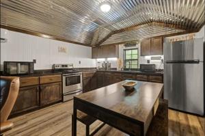 a large kitchen with wooden cabinets and a stainless steel refrigerator at Red River Gorge Creekside Cabin, Hot Tub, Shared Bathhouse in Stanton