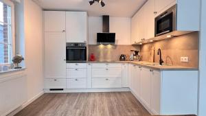 a white kitchen with white cabinets and appliances at Haus Sansibar auf Poel mit Sauna& Kamin, ruhigem Garten-700m vom Strand! in Insel Poel +31 photos
