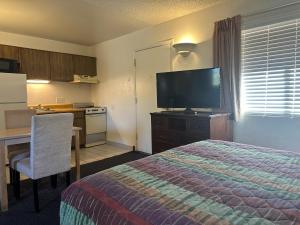 a hotel room with a bed and a desk and a television at Flamingo Suites in Tucson