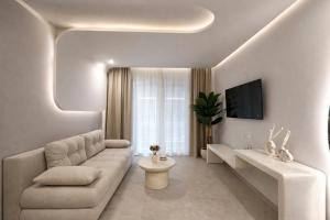 a white living room with a couch and a tv at NOÈA Luxury Suites in Kavála