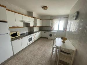 a kitchen with white cabinets and a table and a table and chairs at A Riveira in Muxia +5 photos