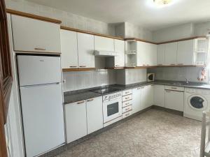 a kitchen with white cabinets and a washer and dryer at A Riveira in Muxia