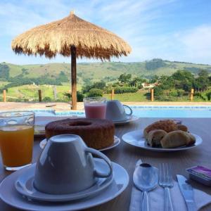 a table with plates of food and an umbrella at Pousada Morada do Sol in Socorro