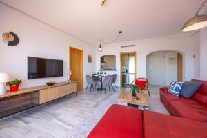 a living room with a red couch and a flat screen tv at Mediterranean & golf dreams in Alicante +22 photos