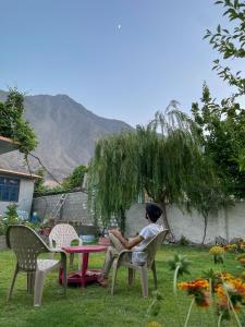 a man sitting at a table in a yard at Mountain Dale Guest House in Gilgit