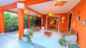 a living room with orange walls and furniture and plants at Terra do Sol Pousada e Hostel in Porto Seguro