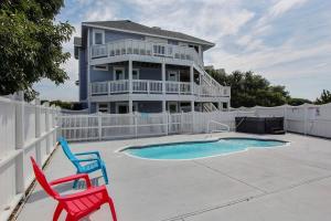 a house with a pool and two chairs in front of it at Seaside Sea Esta in Corolla