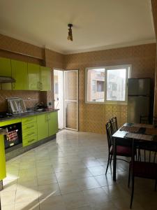a kitchen with green cabinets and a table with chairs at Appartement Moderne à coté de la plage - Essaouira in Essaouira