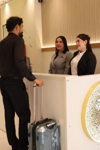 a man standing next to a counter with a person with a suitcase at Cozy 1 Bedroom Hall in Khor Fakkan